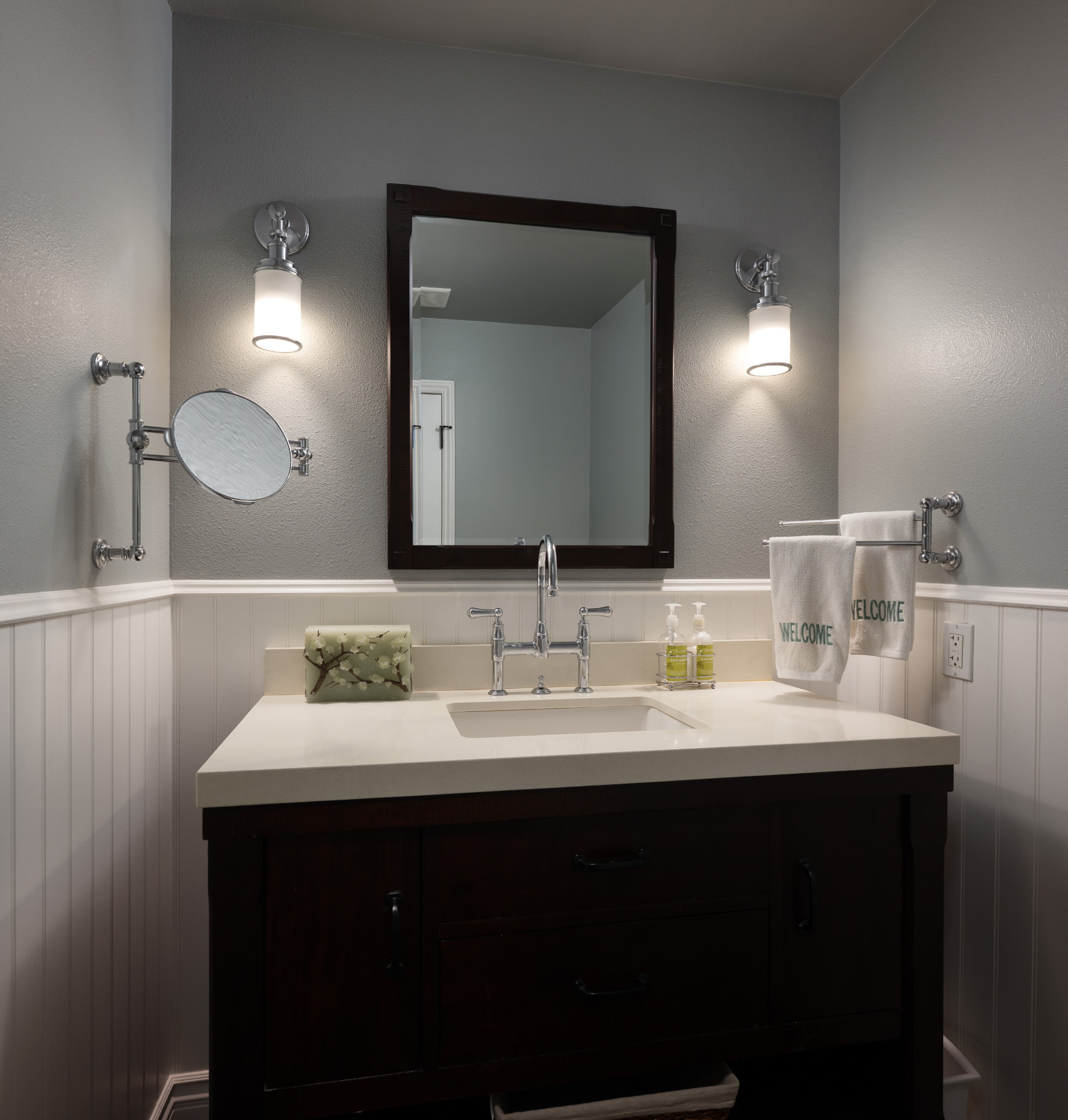 Powder room with dark wood vanity and vintage sconces