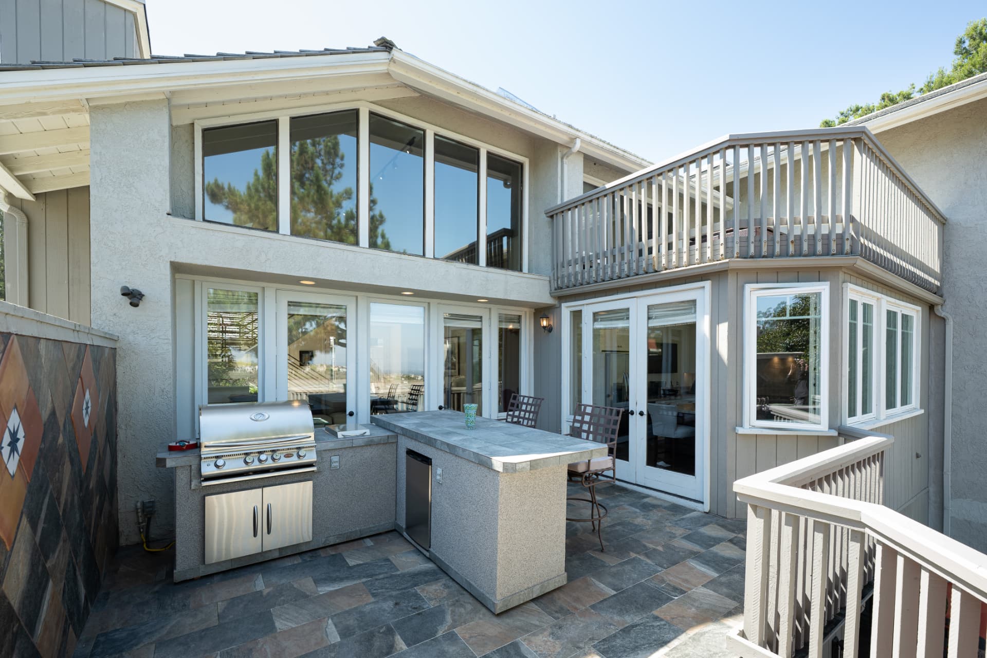 Rear exterior with two-story windows and built-in BBQ on the paver patio